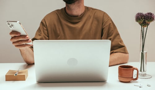 A person using a laptop and mobile phone